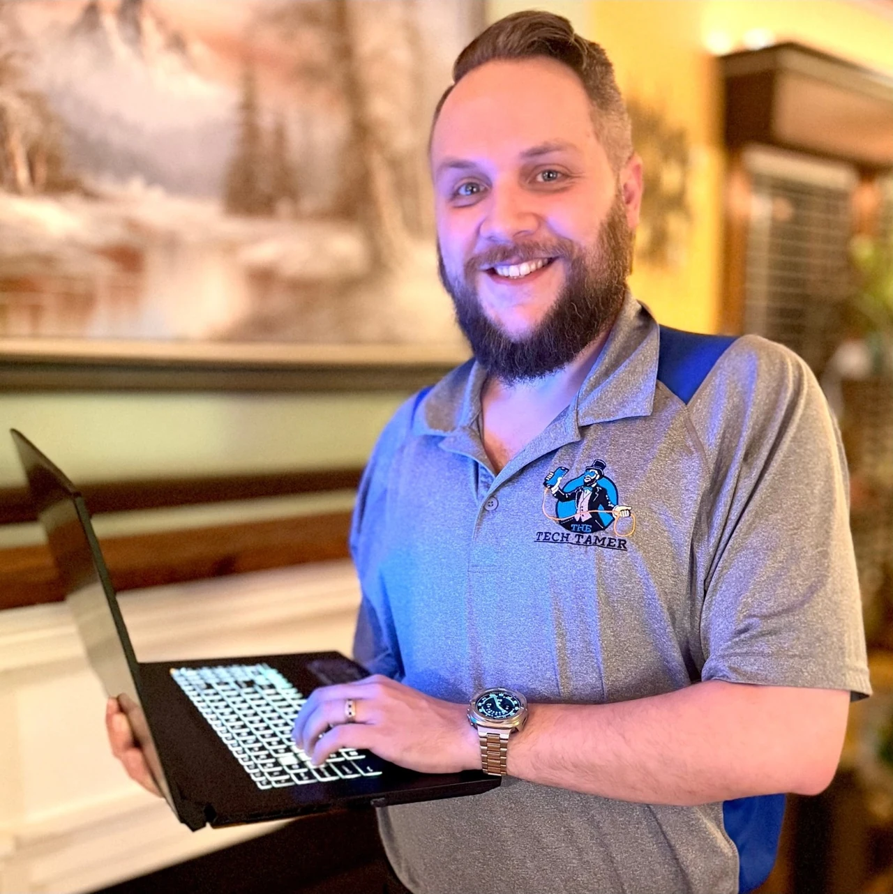 Josh Sargent holding a laptop and wearing his Tech Tamer polo